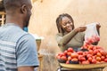 black girl selling tomatoes in a local african market to a customer smiling