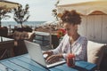 Black girl using laptop in cafe near sea Royalty Free Stock Photo