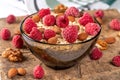 Black glass bowl with oatmeal, raspberries and almonds on an old wooden board Royalty Free Stock Photo