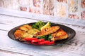 A black glass plate with two grilled chicken fillet steaks with potatoes, broccoli, zucchini, tomato and mushrooms on a wooden Royalty Free Stock Photo