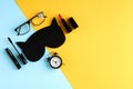 Black glasses, alarm clock, mascara, pomade and sleep mask on blue and yellow background composition Royalty Free Stock Photo