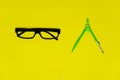 Black glasses and colorful green compasess for circle drawing in school or education colorful yellow background Royalty Free Stock Photo