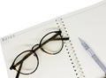 Black glasses eyes and pen on white notebook