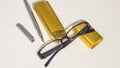 Black glasses, gold case and pen on the white background