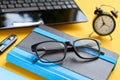 Black glasses, notebook, usb flash and laptop keyboard on blue and yellow background composition Royalty Free Stock Photo