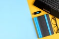 Black glasses, notebook, usb flash and laptop keyboard on blue and yellow background composition Royalty Free Stock Photo