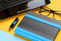 Black glasses, notebook, usb flash and laptop keyboard on blue and yellow background composition Royalty Free Stock Photo