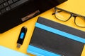 Black glasses, notebook, usb flash and laptop keyboard on blue and yellow background composition Royalty Free Stock Photo