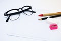 Black glasses, white paper, pencil, pen, pink sharpener Royalty Free Stock Photo