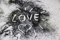 A black glitter on the white background. A heart and word love painted on the black sand Royalty Free Stock Photo