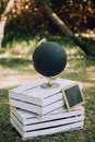 A black globe with a slate stands on wooden pallets on the grass. Wedding Original Decor