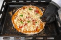 A black-gloved chef prepares pizza