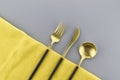 Black and gold cutlery on two tone grey and yellow