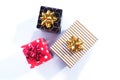 Black and gold, red and white polka dots and white and gold three gift boxes with gold and red bows on a white background