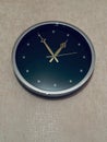 Black and gold wall clock hangs on a tan wall background Royalty Free Stock Photo