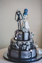 Black gothic wedding cake decorated with figures of cartoon's he