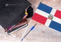 Black graduation hat on books next to Dominican republic flag, education concept Royalty Free Stock Photo