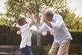 Black grandfather playing with his grandson in a garden