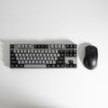Black and gray computer keyboard and wireless mouse on a white surface Royalty Free Stock Photo