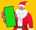 Black gray-haired Santa is holding a phone in his hand. African Santa Claus shows a close-up of a green phone screen to the camera