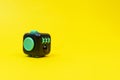 Black and green fidget cube on yellow background Royalty Free Stock Photo