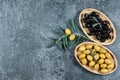 Black and green olives in bamboo bowl with olive tree branch Royalty Free Stock Photo