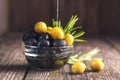 Black and green olives mixed in the bowl on wooden table. Olive oil pouring from olive Royalty Free Stock Photo