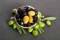 Black and green olives mixed in the porcelain bowl on gray stone Royalty Free Stock Photo