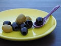 Appetizing olives in a yellow plate on a dark table