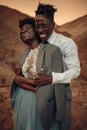 Groom hugs his bride dressed in his jacket in canyon at sunset a