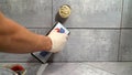 The master rubs the tile with a spatula. Repair and wall tiling. The master rubs the seams of the tiles with black putty Royalty Free Stock Photo