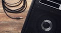 Black guitar amplifier speaker and jack cable on wooden background