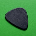 Black guitar pick with a triangular shape, featuring subtle surface texture. Positioned Royalty Free Stock Photo