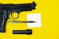 Black gun, reminder note paper, pen and flashlight lies on a yellow background. Private detectives work. Searching information