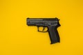 Black gun on a yellow background, concept Royalty Free Stock Photo