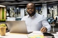 Black guy documenting essential ideas on paper and reading on laptop Royalty Free Stock Photo