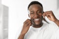 Black Guy Flossing Teeth In Morning Standing In Bathroom Indoors