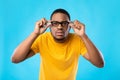 Black Guy In Glasses Squinting Eyes Posing Over Blue Background Royalty Free Stock Photo