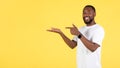 Black Guy Pointing At Hand Holding Invisible Object, Yellow Background Royalty Free Stock Photo
