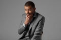 Black guy thinking in gray blazer isolated on gray background