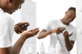 Black Guy Using Aftershave Lotion Standing In Bathroom At Home Royalty Free Stock Photo