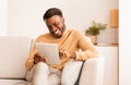 Black Guy Using Tablet Smiling Sitting On Sofa At Home Royalty Free Stock Photo