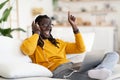 Black Guy Wearing Headphones Relaxing On Couch And Listening Music On Laptop Royalty Free Stock Photo