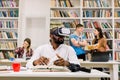 Black guy wearing vr goggles headset, reading book and using information from virtual reality, sitting in modern library Royalty Free Stock Photo