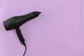 Black hair dryer on lilac paper background Royalty Free Stock Photo