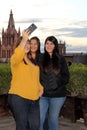 3 black haired latin women, sisters on outdoor terrace taking selfie with view of san miguel de allende parish in guanajoato mexi