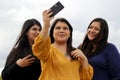 3 black haired latin women, sisters on outdoor terrace taking selfie with view of san miguel de allende parish in guanajoato mexi