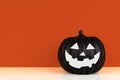 Black Halloween Jack o Lantern decoration on a shelf against an autumn orange background Royalty Free Stock Photo