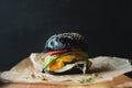 black hamburger on a wooden board on black background