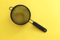 Black hand strainer isolated over a yellow background